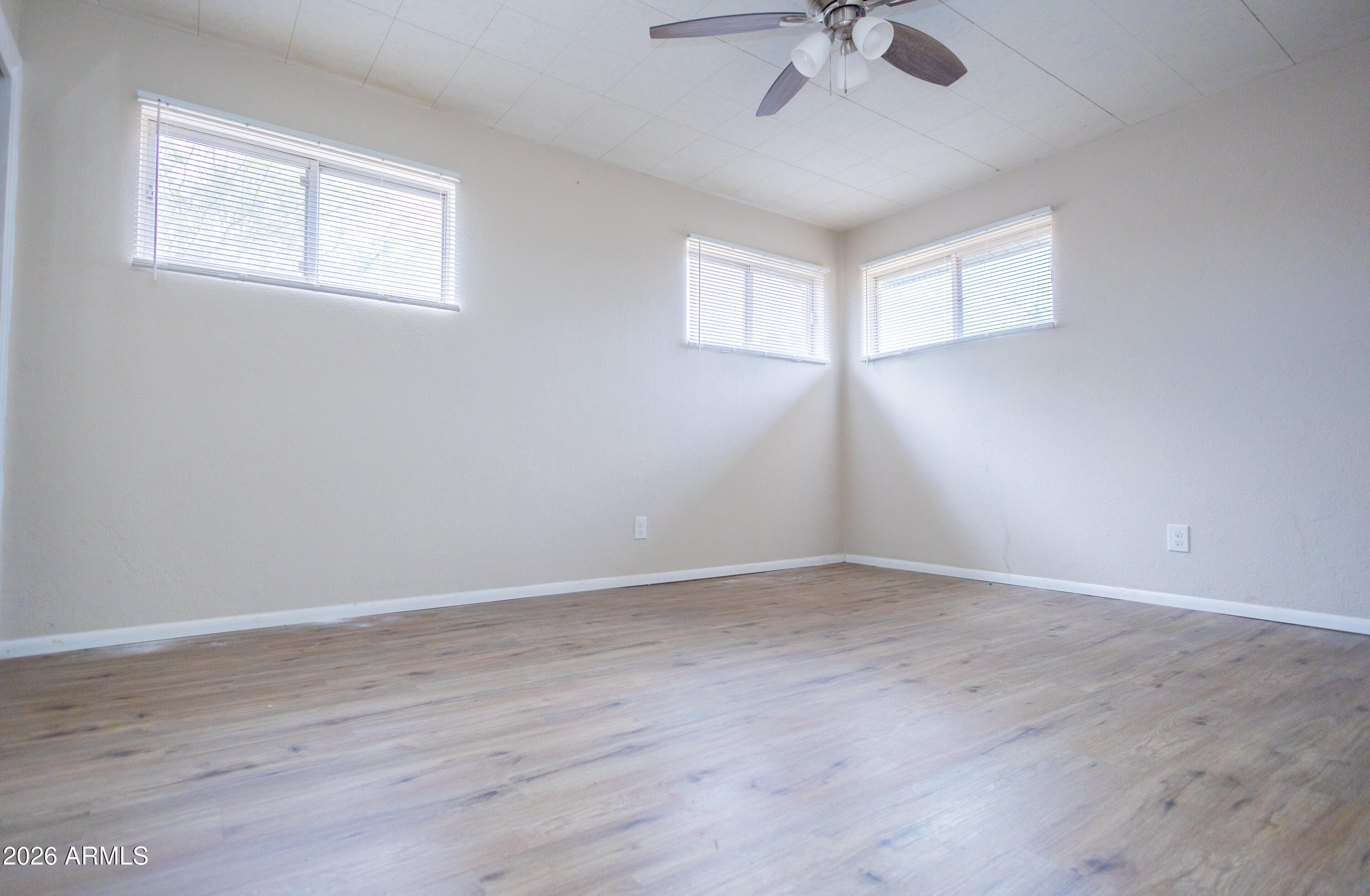 1626 11th Street Douglas, AZ 85607 - Photo 19 of 30 an empty room with wooden floor chandelier fan and windows