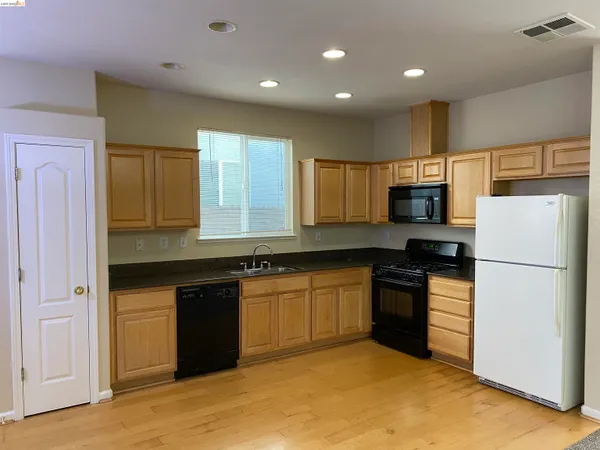 a kitchen with granite countertop a refrigerator stove top oven and sink