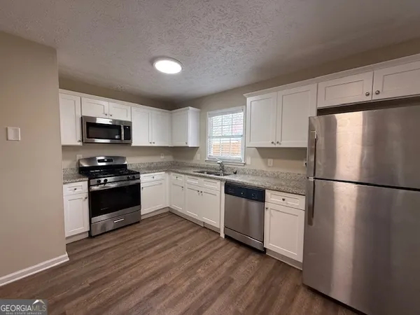 a kitchen with granite countertop a refrigerator stove top oven and sink