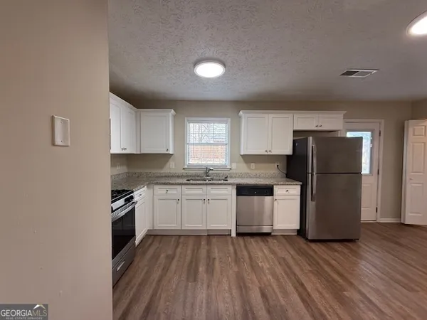 a kitchen with a refrigerator a stove top oven a sink and cabinets with wooden floor