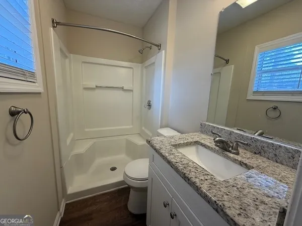 a bathroom with a granite countertop sink toilet and shower