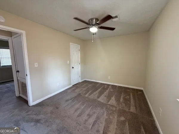 an empty room with closet and a ceiling fan