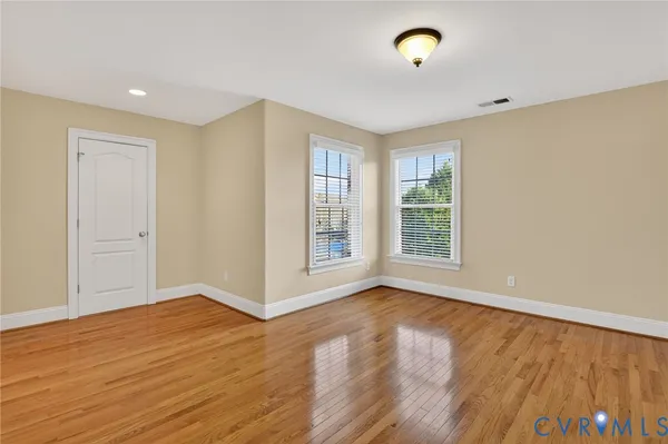 an empty room with chandelier fan and windows