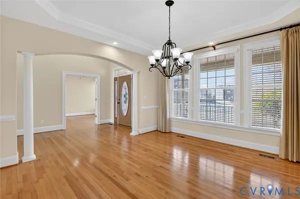 an empty room with wooden floor fireplace and windows