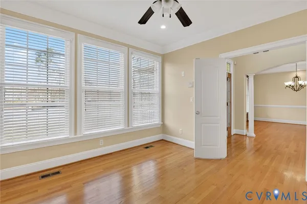 an empty room with wooden floor and windows