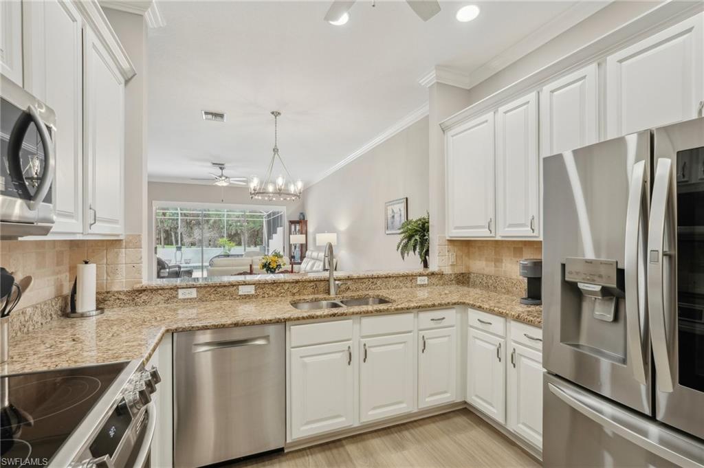 3653 Periwinkle Way Naples, FL 34114 - Photo 12 of 49 Kitchen with backsplash, ceiling fan, appliances with stainless steel finishes, white cabinets, and ornamental molding