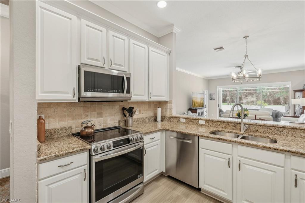 3653 Periwinkle Way Naples, FL 34114 - Photo 13 of 49 Kitchen featuring stainless steel appliances, white cabinets, backsplash, and ornamental molding