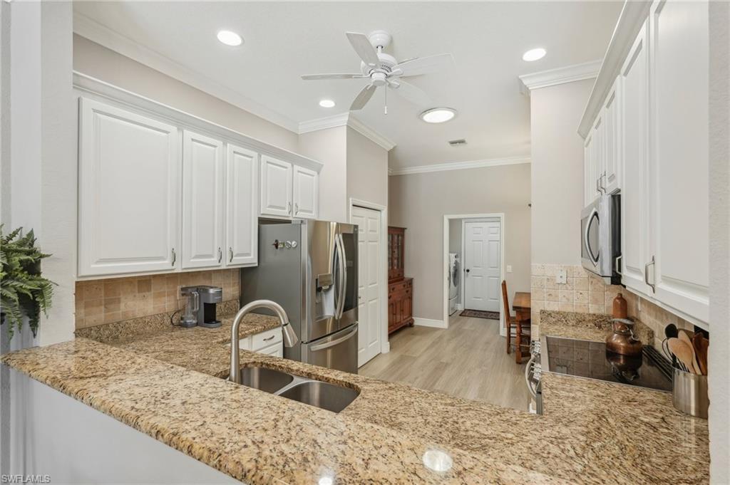 3653 Periwinkle Way Naples, FL 34114 - Photo 14 of 49 Kitchen featuring tasteful backsplash, ornamental molding, white cabinets, stainless steel appliances, and light stone counters