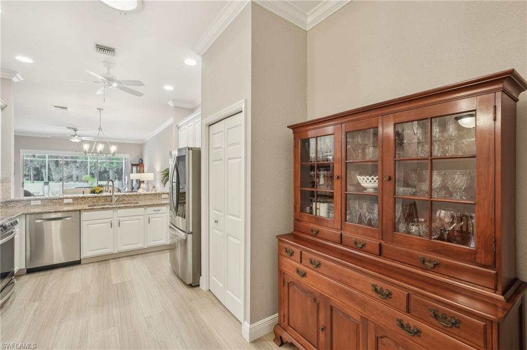 3653 Periwinkle Way Naples, FL 34114 - Photo 15 of 49 Kitchen with ornamental molding, stainless steel appliances, decorative light fixtures, light stone counters, and light wood-style floors