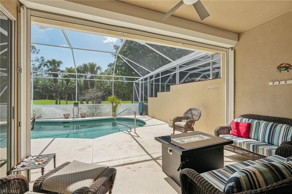 3653 Periwinkle Way Naples, FL 34114 - Photo 29 of 49 Swimming pool featuring a patio area, an outdoor living space with a fire pit, a sunroom, and glass enclosure