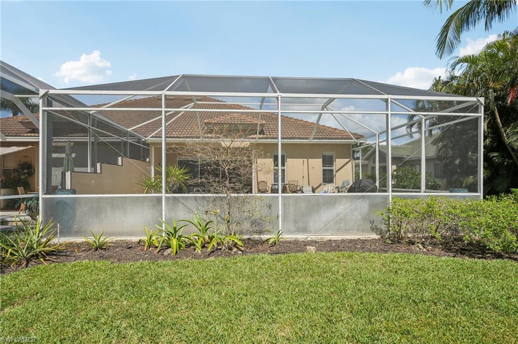3653 Periwinkle Way Naples, FL 34114 - Photo 35 of 49 Rear view of house with a sunroom, a lanai, a lawn, stucco siding, and a patio