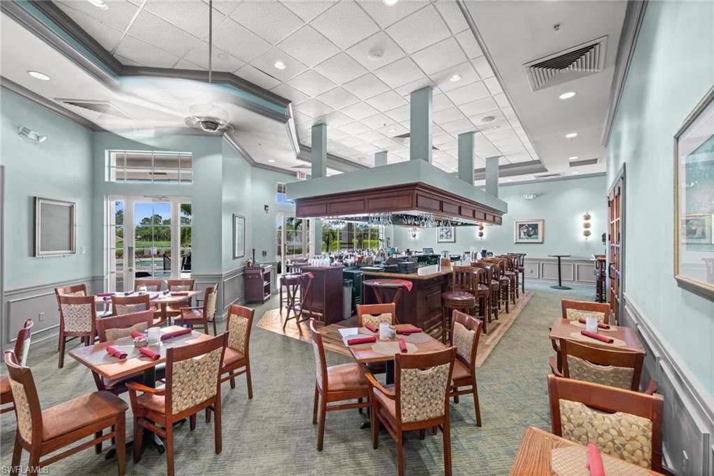 3653 Periwinkle Way Naples, FL 34114 - Photo 47 of 49 Dining area featuring a decorative wall, a wainscoted wall, a dry bar, carpet floors, and a drop ceiling