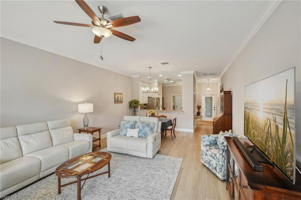 3653 Periwinkle Way Naples, FL 34114 - Photo 5 of 49 Living area featuring crown molding, light wood finished floors, a ceiling fan, and a chandelier