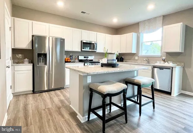 a kitchen with kitchen island granite countertop wooden cabinets and stainless steel appliances