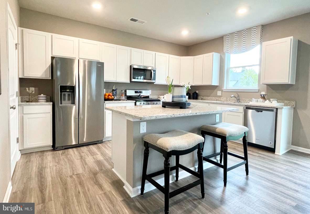 1145 Wintermead Loop Salisbury, MD 21801 - Photo 15 of 51 a kitchen with stainless steel appliances a dining table chairs refrigerator microwave and cabinets