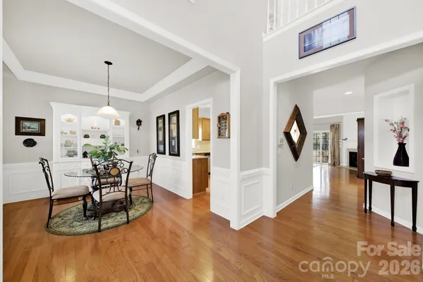 a dining room with wooden floor a chandelier a glass table and chairs