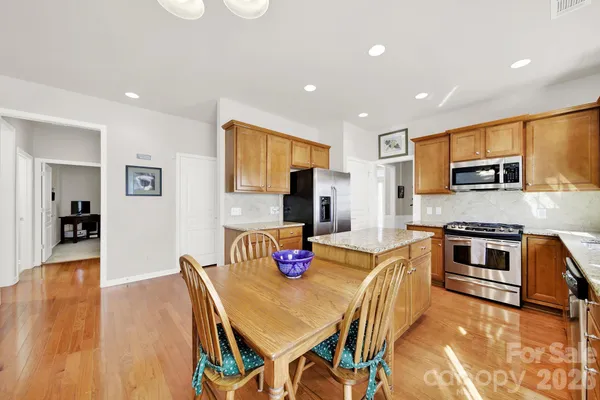 a kitchen with stainless steel appliances granite countertop a stove top oven a sink a dining table and chairs