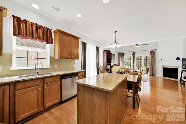 a large kitchen with kitchen island granite countertop a stove a sink a dining table and chairs