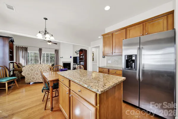 a kitchen with stainless steel appliances granite countertop sink refrigerator and dining table