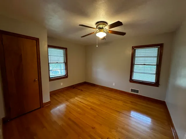 a view of an empty room with window and wooden floor