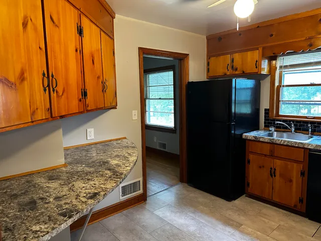 a kitchen with granite countertop a refrigerator and a stove top oven