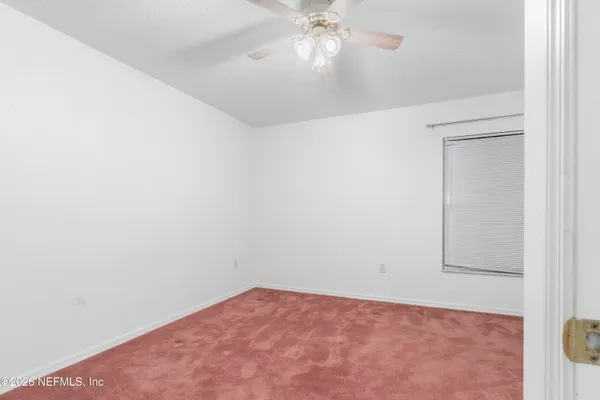 an empty room with a chandelier fan and closet