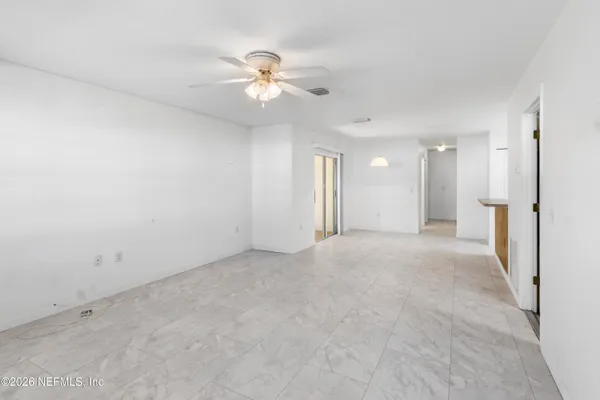 a view of an empty room with a chandelier fan