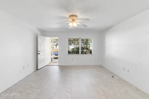 an empty room with chandelier fan and windows