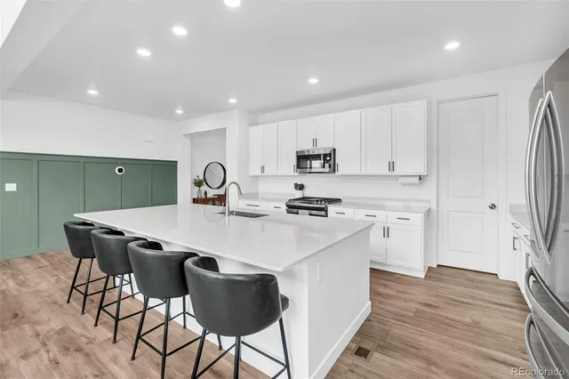 a large kitchen with stainless steel appliances lots of counter top space a sink cabinets and wooden floor