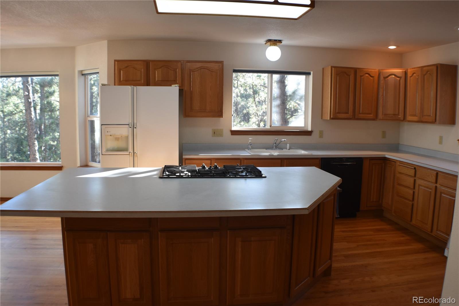 14540 Rosholt Loop Colorado Springs, CO 80921 - Photo 5 of 50 a view of kitchen with kitchen island a sink wooden floor and a large window