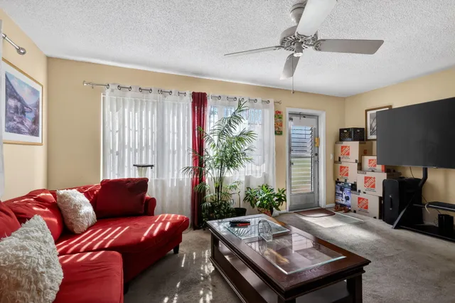 a living room with furniture a flat screen tv and a large window