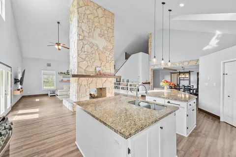 a large kitchen with kitchen island a stove a sink dishwasher and a refrigerator with wooden floor