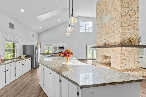 a large white kitchen with lots of counter top space and stainless steel appliances