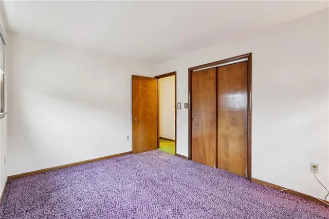 a view of an empty room with closet and a window