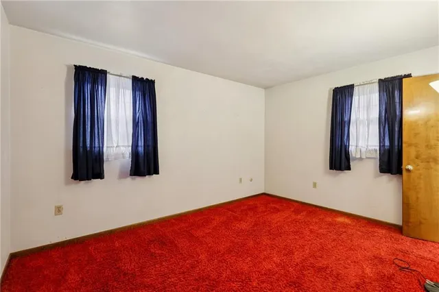 a view of an empty room with wooden floor and windows
