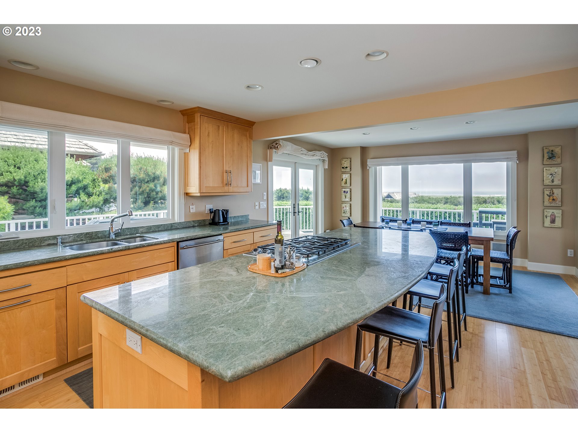 4710 High Ridge Road Gearhart, OR 97138 - Photo 14 of 44 a kitchen with stainless steel appliances granite countertop a stove a sink a dining table and chairs with wooden floor