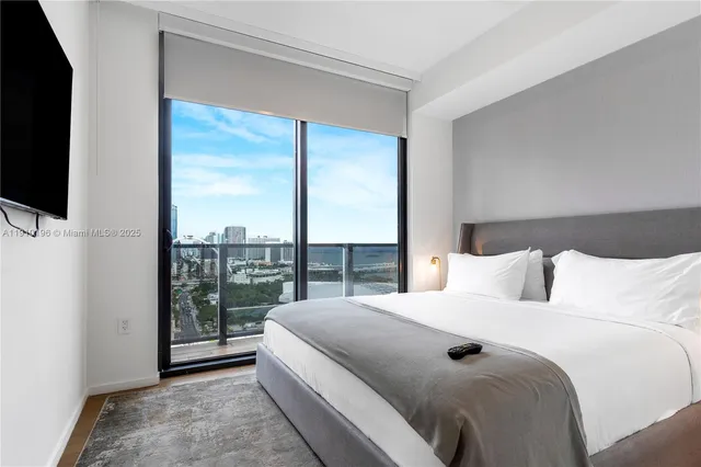 a bedroom with a bed and a flat tv screen next to a window