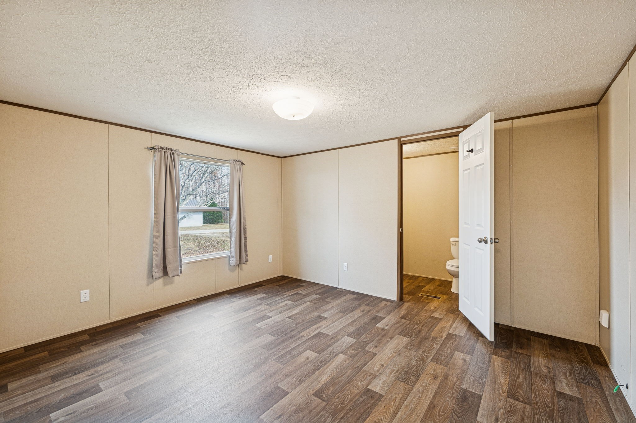 108 Lyell Road Hohenwald, TN 38462 - Photo 10 of 25 a view of an empty room with wooden floor and a window