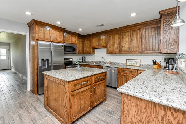 a kitchen with stainless steel appliances granite countertop a kitchen island hardwood floor sink stove and granite counter top