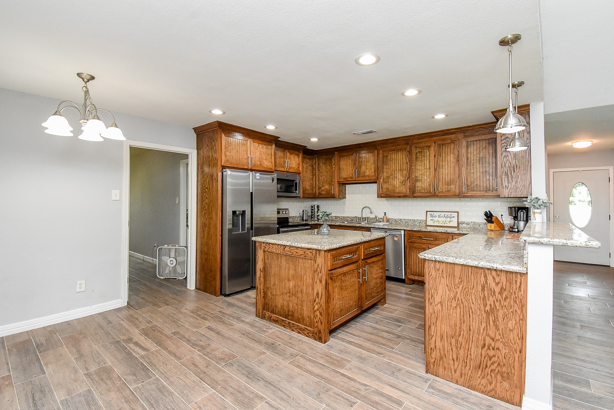 3818 County Road 36 Angleton, TX 77515 - Photo 8 of 49 a large kitchen with stainless steel appliances granite countertop a stove a refrigerator a sink dishwasher and a oven with wooden floor