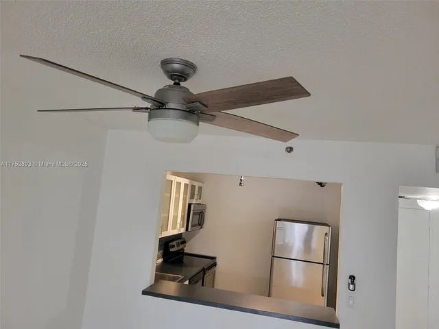 a kitchen with a refrigerator and a ceiling fan
