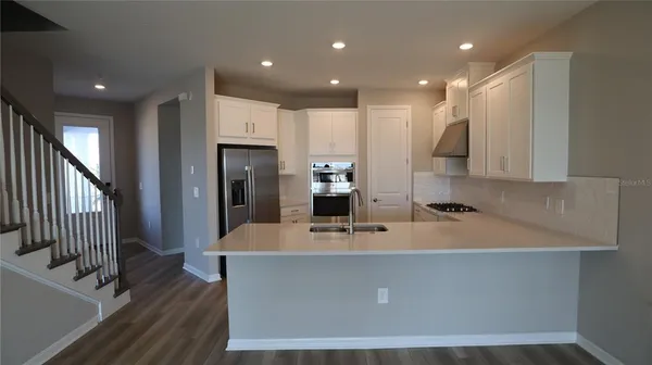 a large kitchen with stainless steel appliances a large counter top a refrigerator and a sink