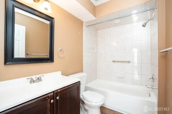 a bathroom with a bathtub shower sink vanity mirror and toilet
