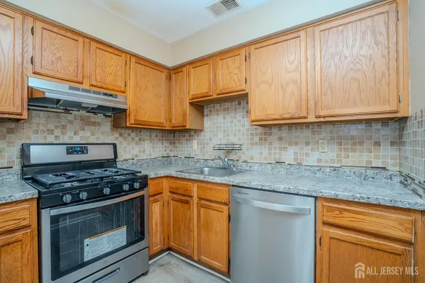 a kitchen with stainless steel appliances granite countertop a stove a sink and cabinets