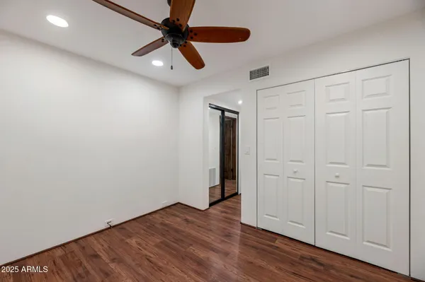 an empty room with wooden floor cabinet and windows