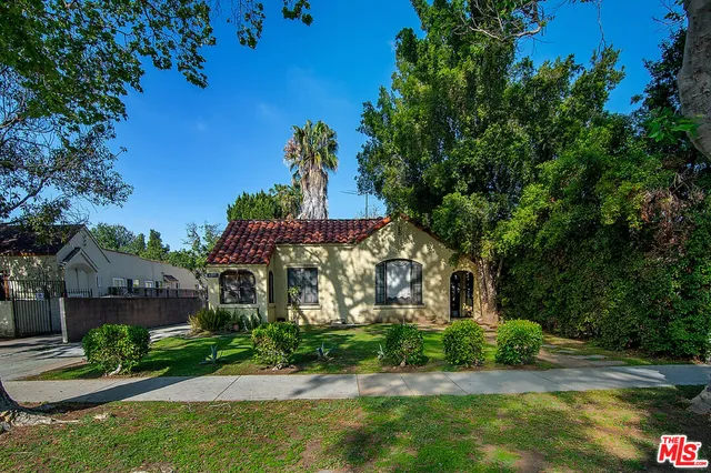 a front view of a house with a yard and potted plants