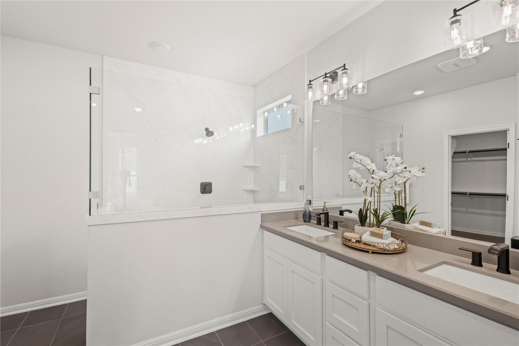 1128 Villa Rialto View Leander, TX 78641 - Photo 28 of 40 Modern bathroom featuring dual vanities, a spacious walk-in shower, and ample storage solutions.