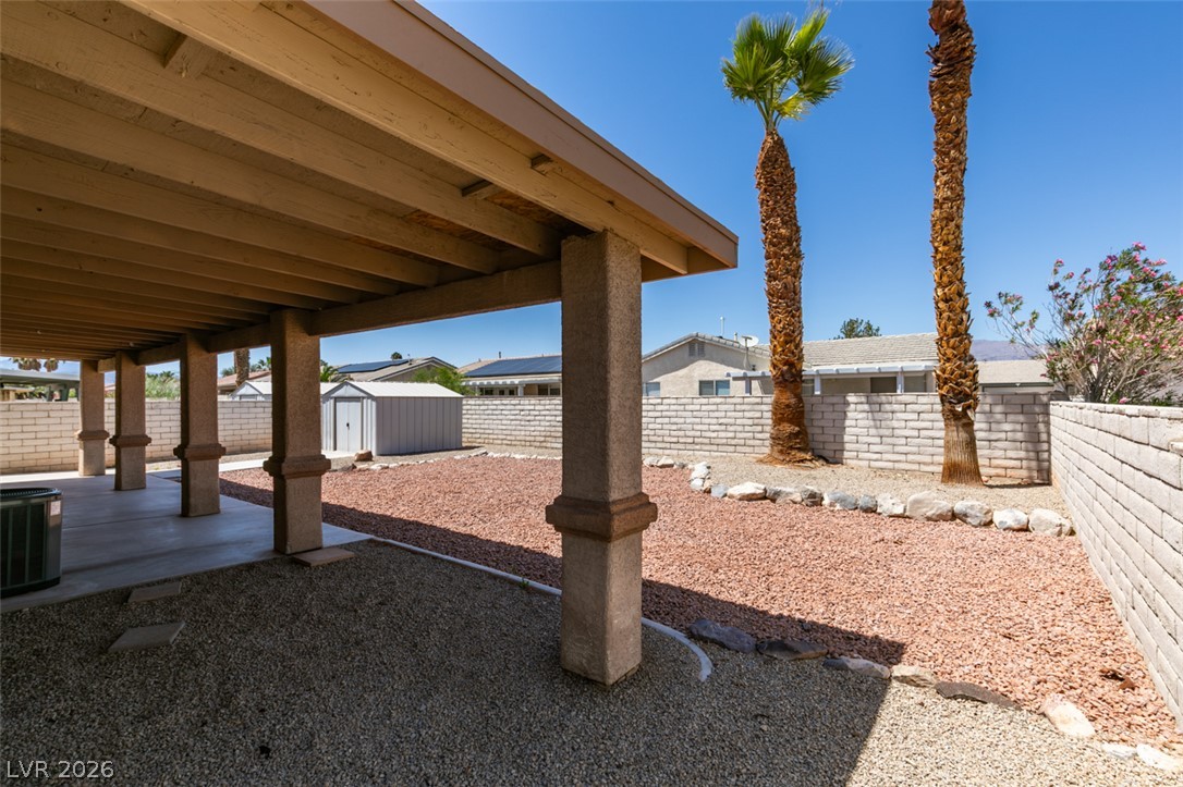 2028 Rustler Ridge Avenue North Las Vegas, NV 89031 - Photo 36 of 40 A spacious backyard patio provides ample shade and privacy, featuring desert-friendly landscaping with palm trees.