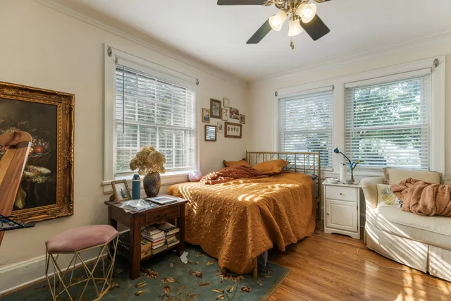 an empty room with wooden floor ceiling fan and windows