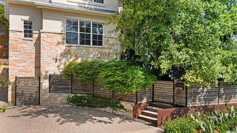 1609 Hartford Road, Unit A Austin, TX 78703 - Photo 3 of 39 A stone and stucco facade complements the wooden fencing, offering inviting outdoor pathways.